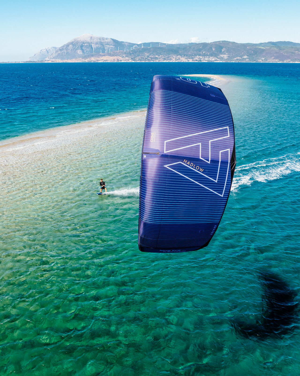 Drone shot of Aaron Hadlow kiteboarding along the coastline